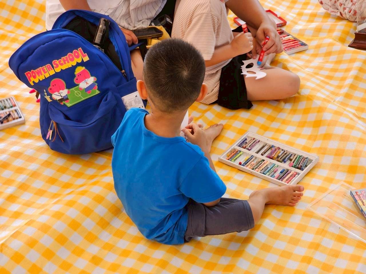 孩子坐在野餐墊上畫畫